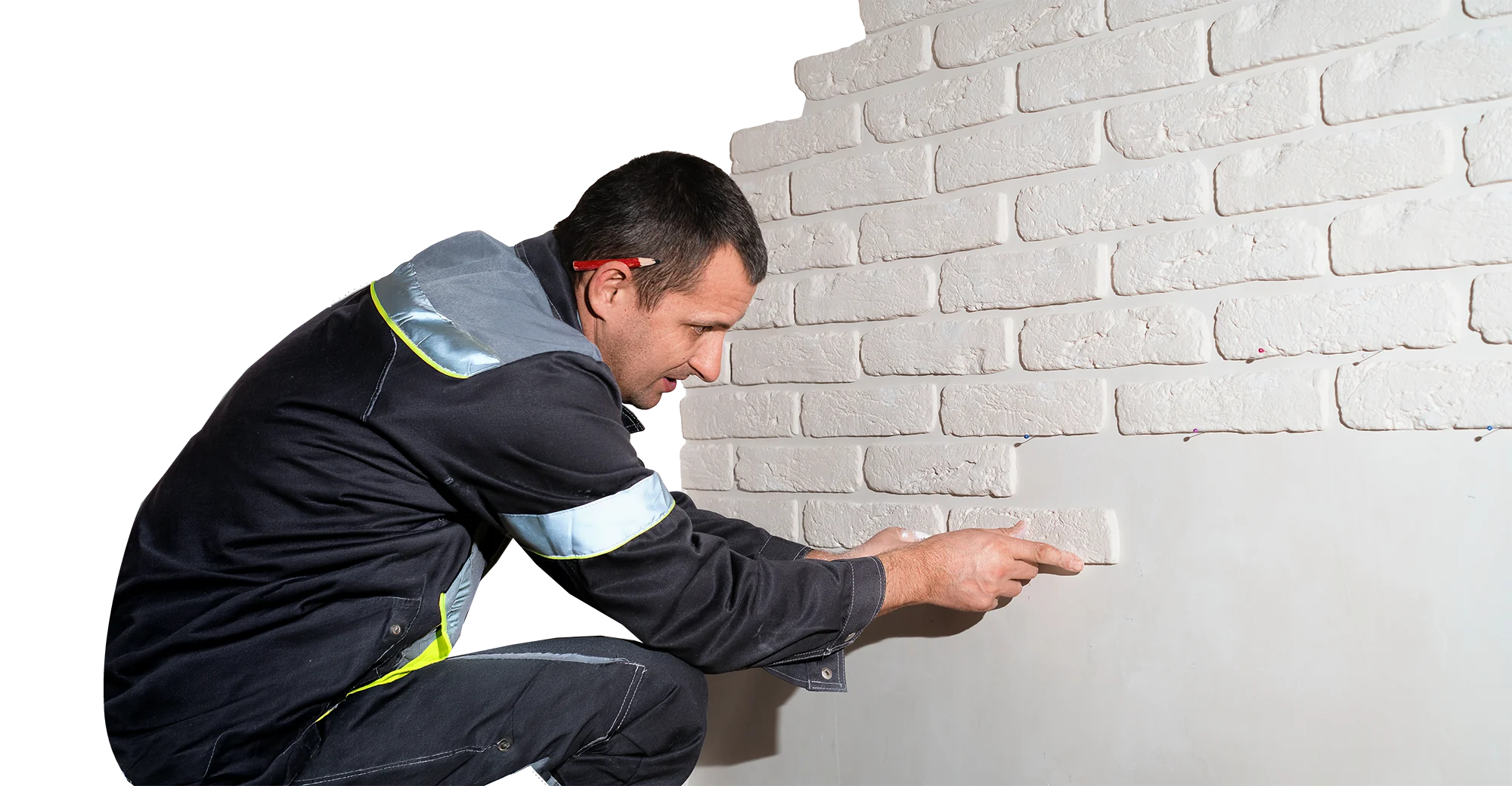 Artisan appliquant un enduit sur un mur en briques blanches