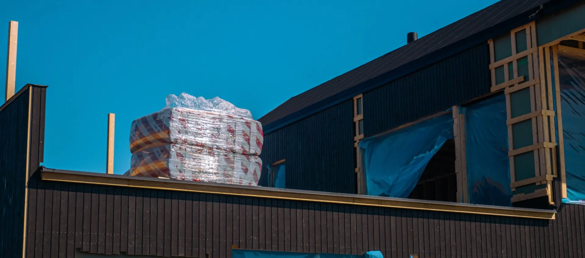 Maison en chantier avec bardage sombre et matériaux isolants sur le toit