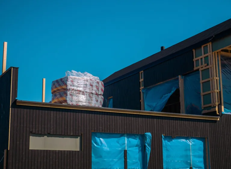 Maison en chantier avec bardage sombre et matériaux isolants sur le toit