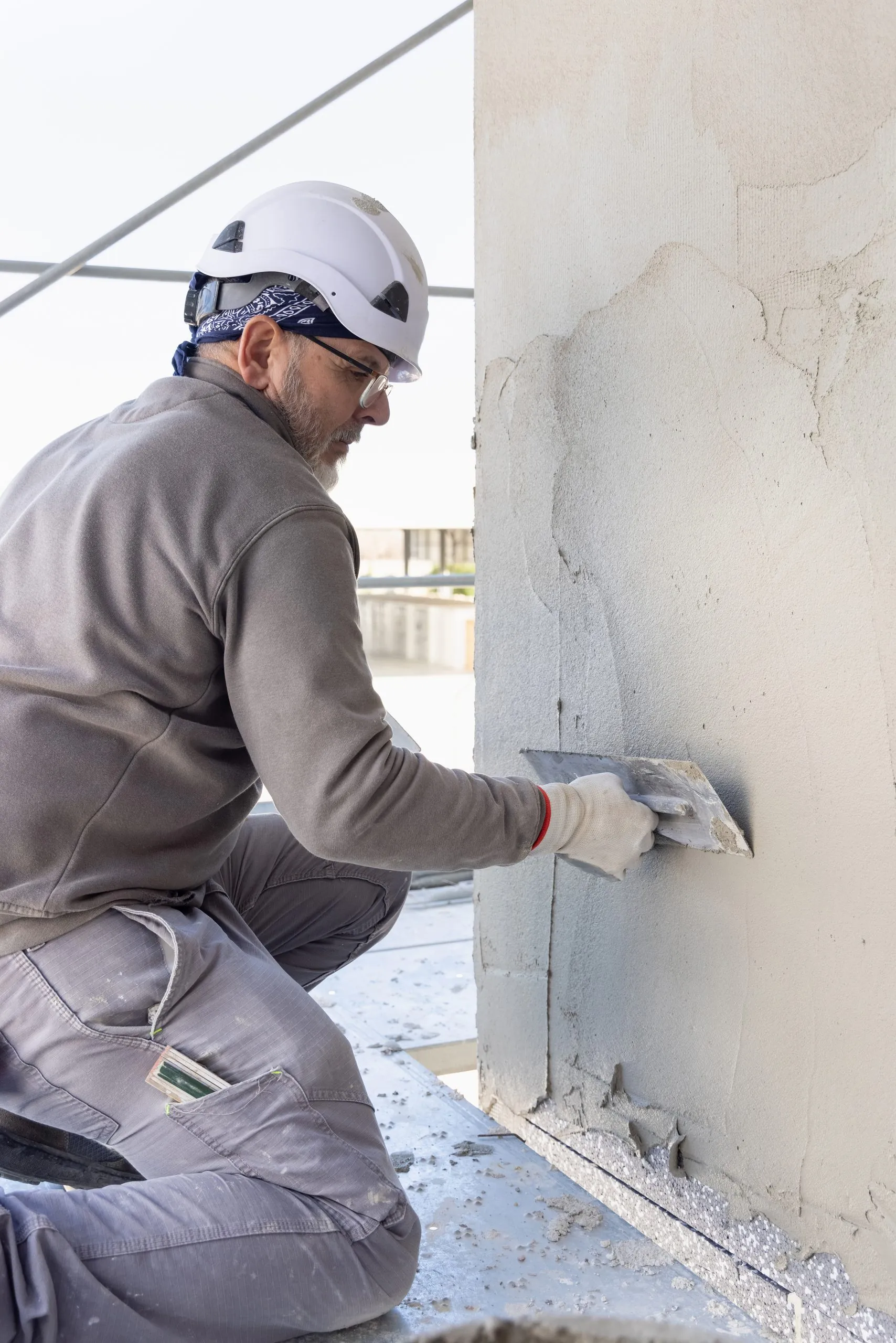 Façadier lissant un enduit sur un mur