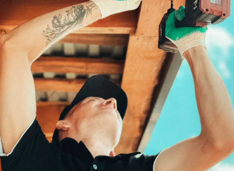 Artisan fixant un lambris PVC sous un débord de toit