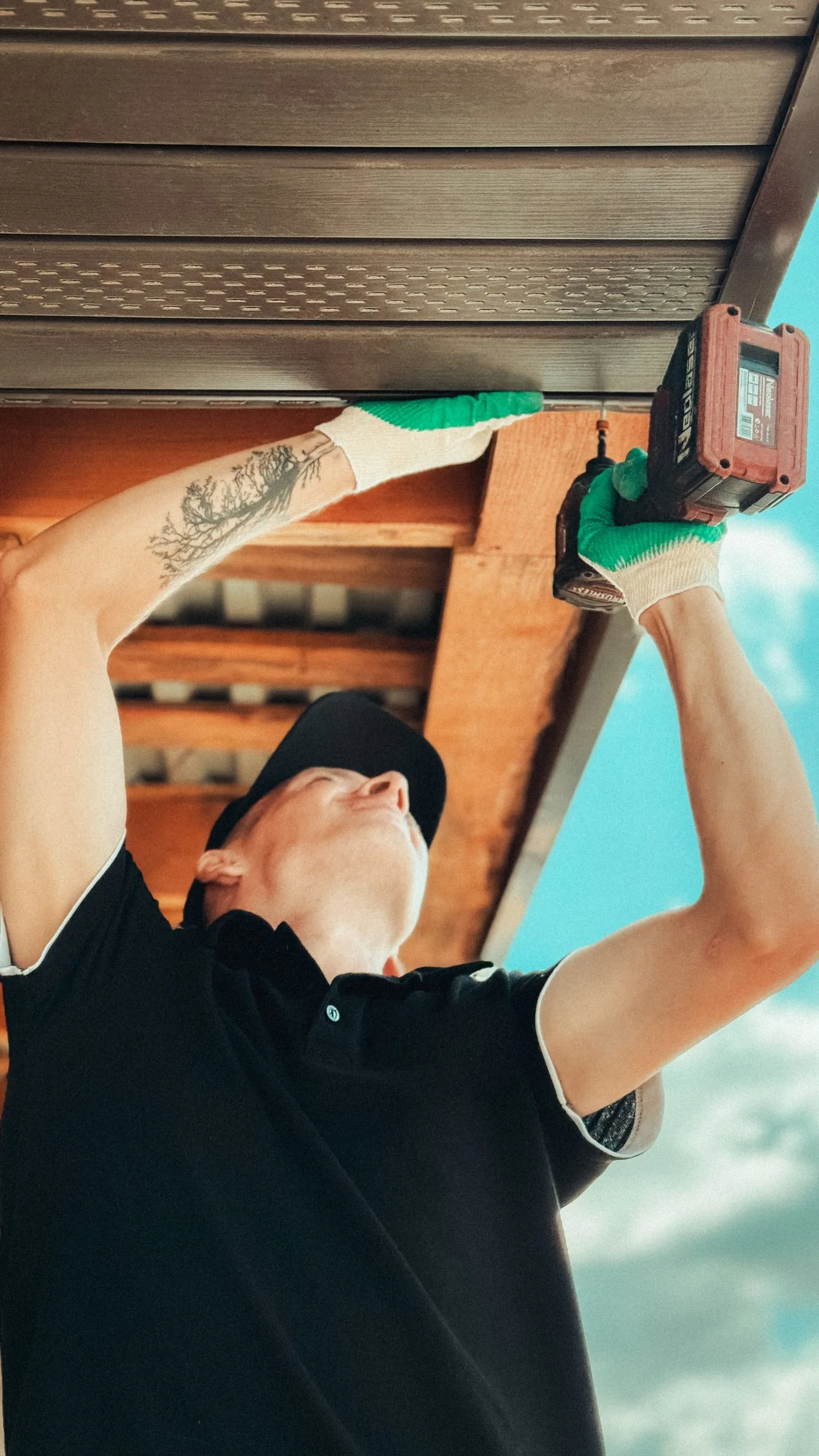 Artisan fixant un lambris PVC sous un débord de toit